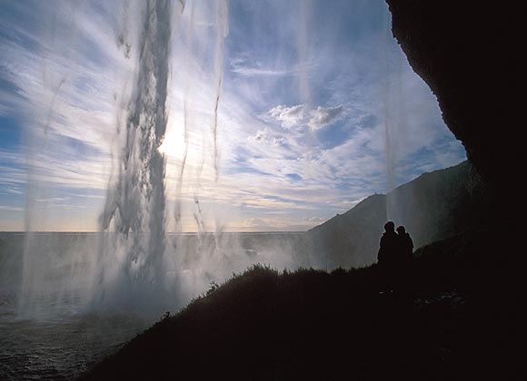 Touristen stehen unter einem Felsüberhang am Seljalandsfoss bei Seljaland im Süden Islands, aufgenommen am 28.06.2006.